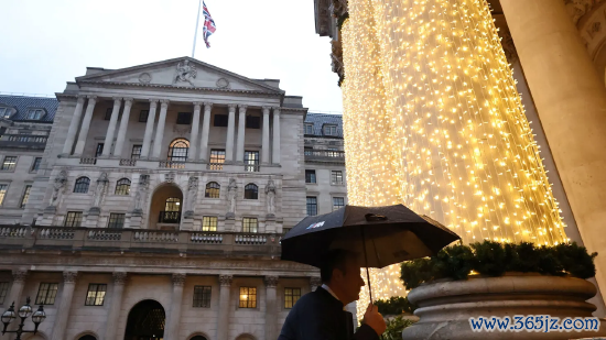 2025 年 12 月 18 日英国伦敦，英国央行货币策略委员会降息当日，别称路东谈主撑伞走过英国央行大楼。